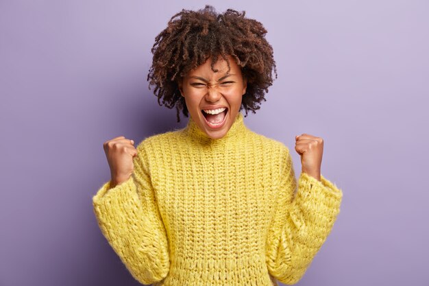 Giovane donna con taglio di capelli afro che indossa un maglione giallo