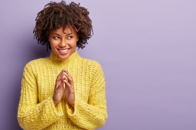 Giovane donna con taglio di capelli afro che indossa un maglione giallo