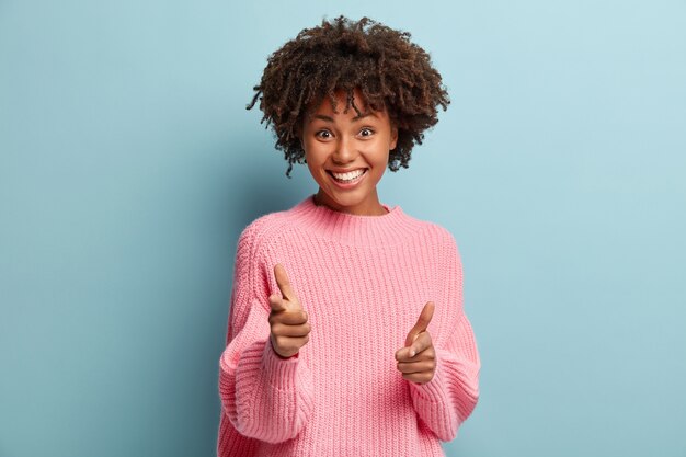 Giovane donna con taglio di capelli afro che indossa un maglione rosa