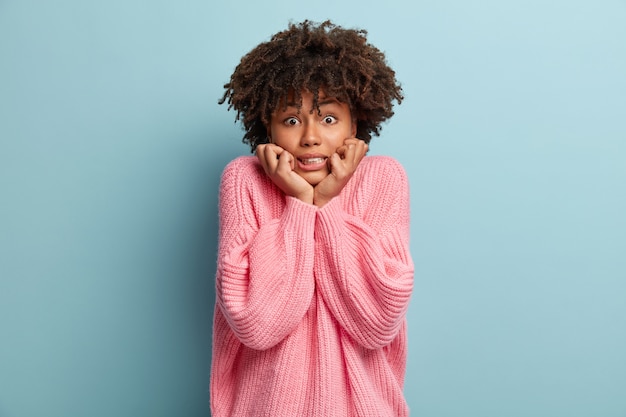 Giovane donna con taglio di capelli afro che indossa un maglione rosa