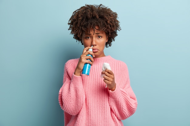 Giovane donna con taglio di capelli afro che indossa un maglione rosa