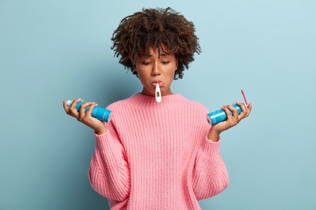 Giovane donna con taglio di capelli afro che indossa un maglione rosa