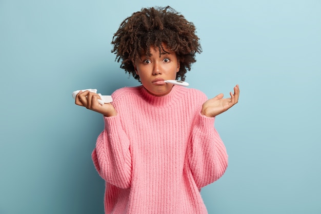 Giovane donna con taglio di capelli afro che indossa un maglione rosa