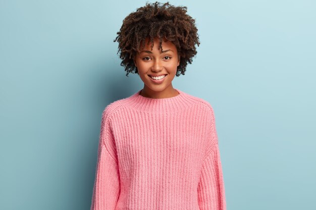 Giovane donna con taglio di capelli afro che indossa un maglione rosa