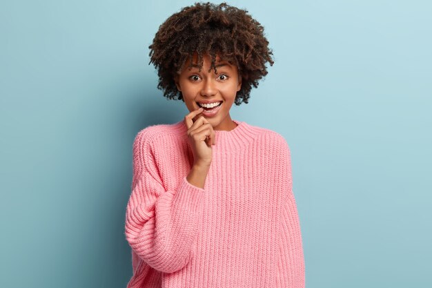 Giovane donna con taglio di capelli afro che indossa un maglione rosa