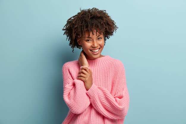 Giovane donna con taglio di capelli afro che indossa un maglione rosa