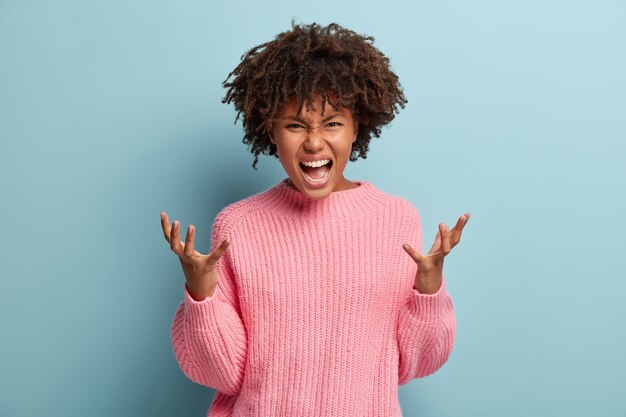 Giovane donna con taglio di capelli afro che indossa un maglione rosa