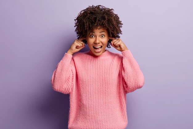 Giovane donna con taglio di capelli afro che indossa un maglione rosa