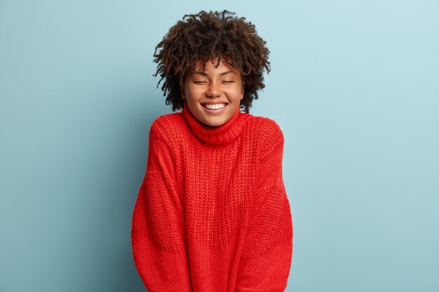 Giovane donna con taglio di capelli afro che indossa un maglione rosso