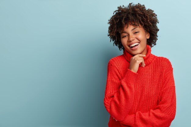 Giovane donna con taglio di capelli afro che indossa un maglione rosso