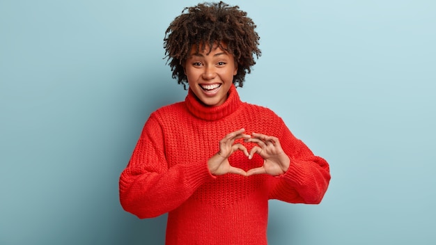 Giovane donna con taglio di capelli afro che indossa un maglione rosso