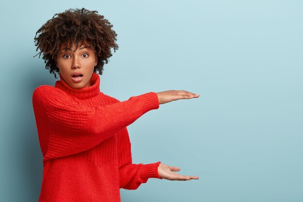 Giovane donna con taglio di capelli afro che indossa un maglione rosso