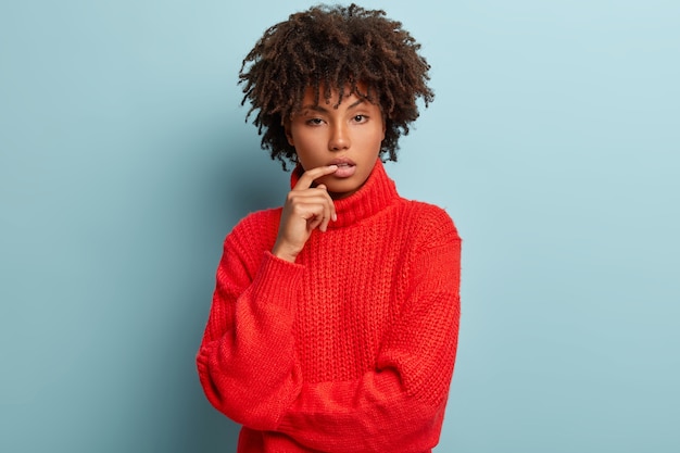 Giovane donna con taglio di capelli afro che indossa un maglione rosso