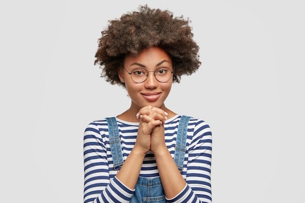 Giovane donna con taglio di capelli afro che indossa una tuta in denim