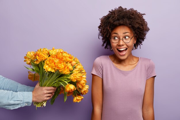 Giovane donna con taglio di capelli afro che riceve bouquet di fiori