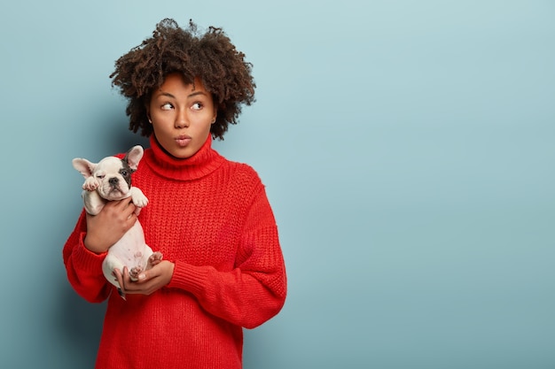 Giovane donna con taglio di capelli afro che tiene piccolo cane