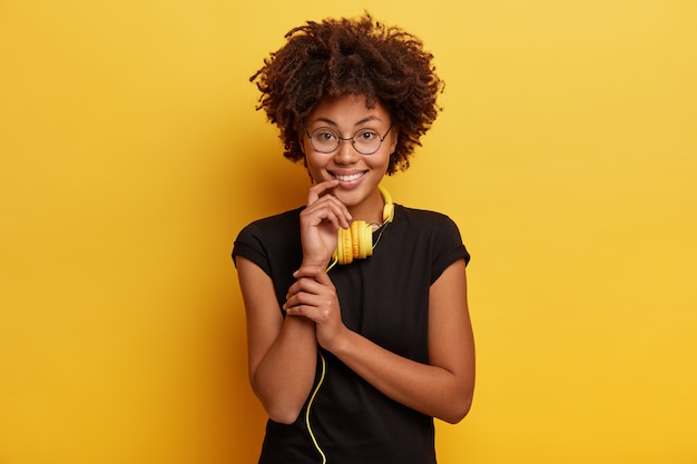 Giovane donna con taglio di capelli afro con cuffie gialle