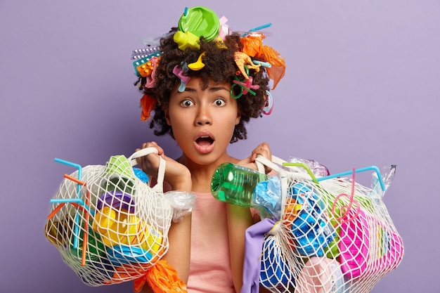 Giovane donna con taglio di capelli afro e rifiuti di plastica tra i capelli