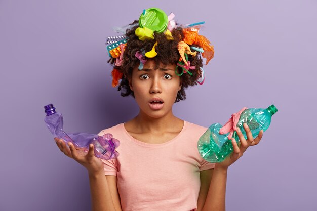 Giovane donna con taglio di capelli afro e rifiuti di plastica tra i capelli