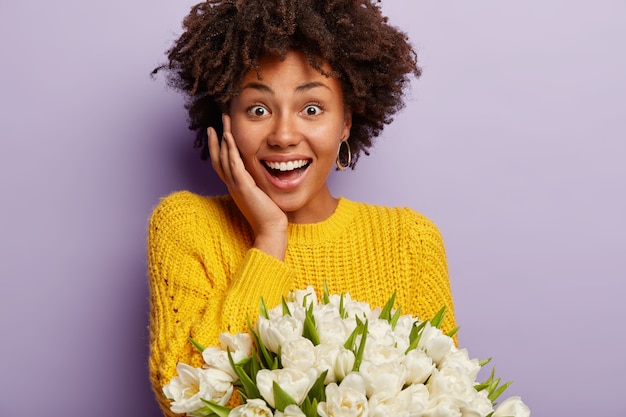 Giovane donna con taglio di capelli afro holding bouquet di fiori bianchi