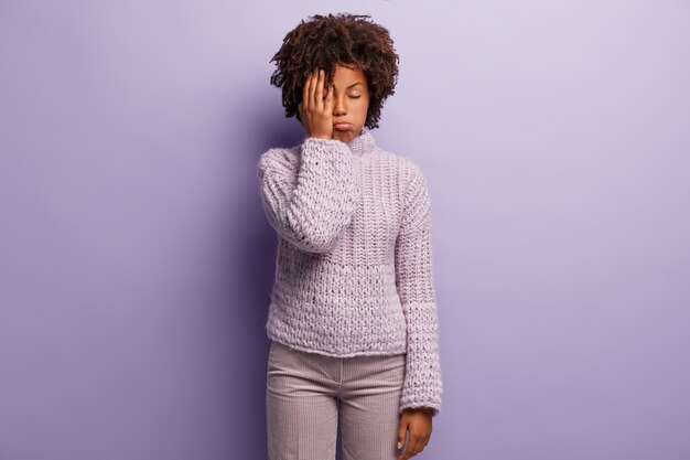 Giovane donna con taglio di capelli afro indossa un maglione viola