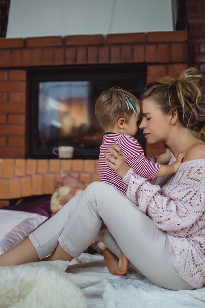 giovane donna con un bambino. Mamma e figlio stanno scherzando, divertendosi vicino al camino.