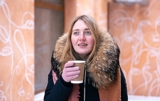 Giovane donna con un bicchiere di bevanda calda in inverno primo piano