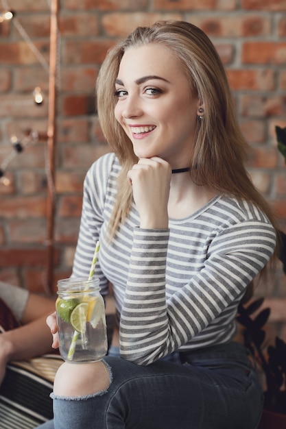Giovane donna con un drink e festeggia al bar
