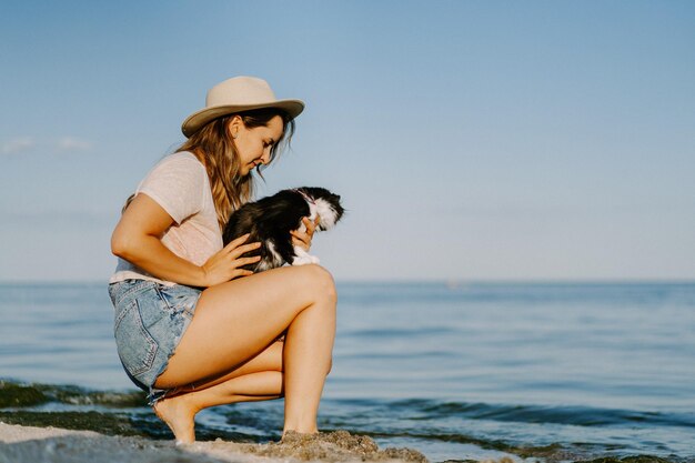 giovane donna con un gatto sulla spiaggia vicino al mare. Concetto di viaggio con un animale domestico.