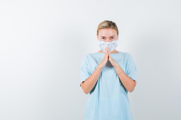 Giovane donna con una maschera medica che prega