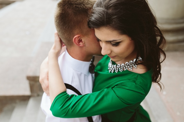 Giovane donna con vestito verde abbraccia il suo ragazzo