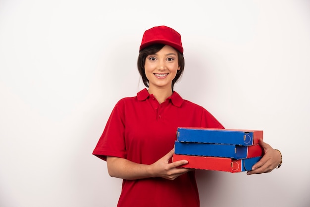 Giovane donna consegna pizza in possesso di tre cartoni di pizza.