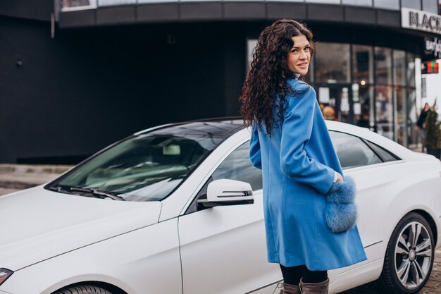 Giovane donna d'affari felice che esce dalla sua auto