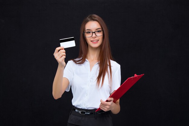 Giovane donna d'affari in bicchieri con carta di credito e appunti per appunti
