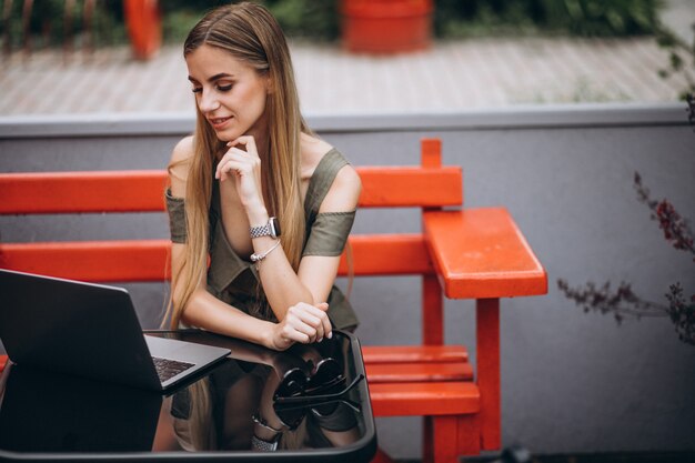 Giovane donna d'affari, lavorando su un computer portatile fuori in un caffè