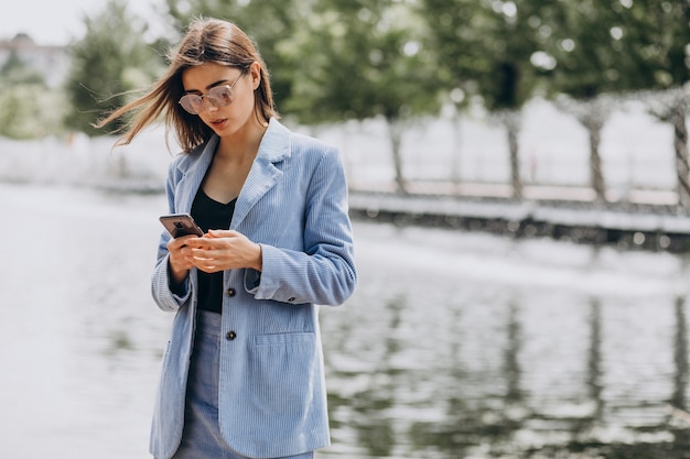 Giovane donna d'affari utilizzando il telefono nel parco