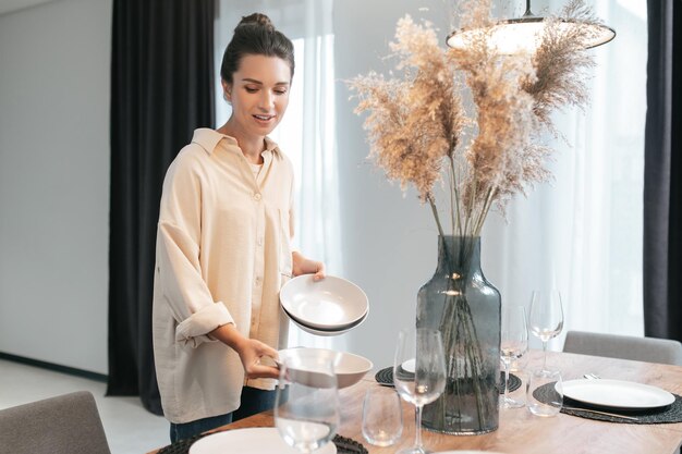 Giovane donna dai capelli scuri che serve il tavolo in cucina