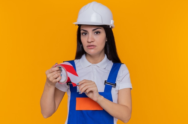 Giovane donna del costruttore in uniforme da costruzione e casco di sicurezza
