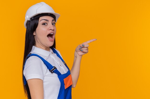 Giovane donna del costruttore in uniforme da costruzione e casco di sicurezza