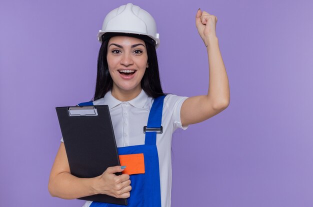 Giovane donna del costruttore in uniforme della costruzione