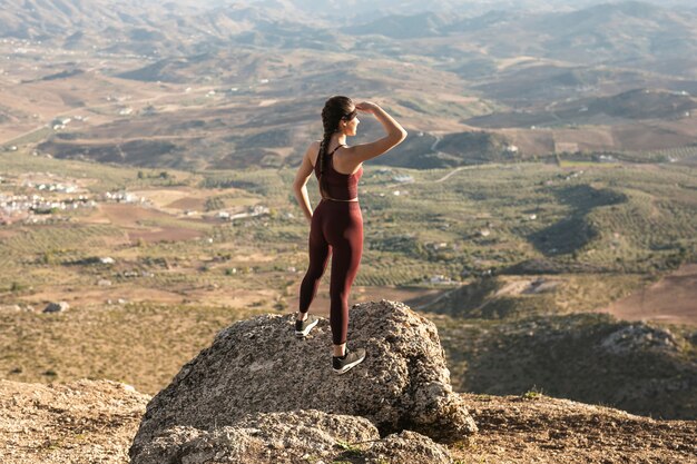 Giovane donna dell'angolo alto sul distogliere lo sguardo della montagna