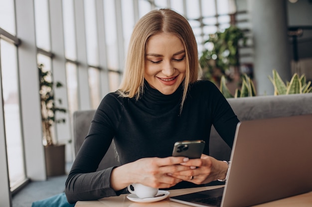 Giovane donna di affari che lavora al computer portatile in un caffè