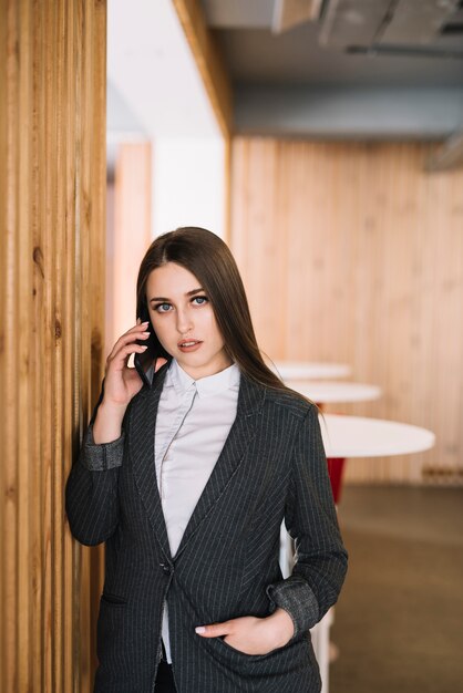 Giovane donna di affari che parla dal telefono alla parete