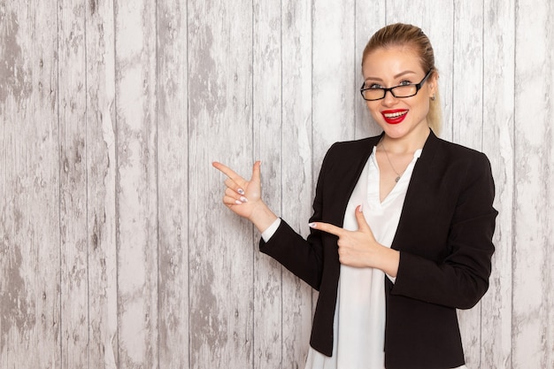 Giovane donna di affari di vista frontale in giacca nera vestiti rigorosi con occhiali da sole ottici sulla riunione d'affari femminile ufficio lavoro lavoro scrivania bianca