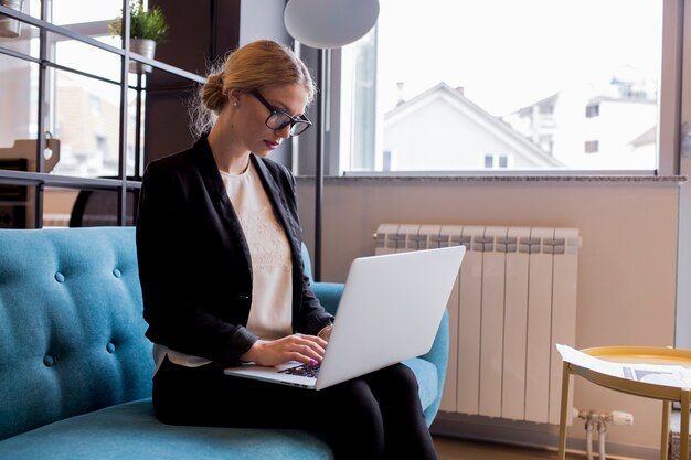 Giovane donna di affari moderna che utilizza computer portatile nell&#39;ufficio