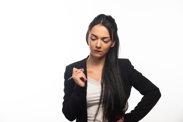 Giovane donna di affari pensierosa in camicia bianca sullo studio bianco della parete