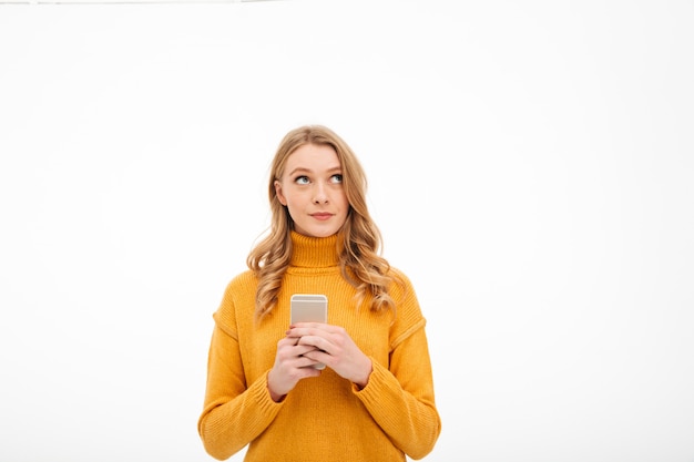 Giovane donna di pensiero che per mezzo del telefono cellulare.