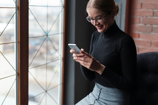 Giovane donna di smiley che per mezzo del telefono