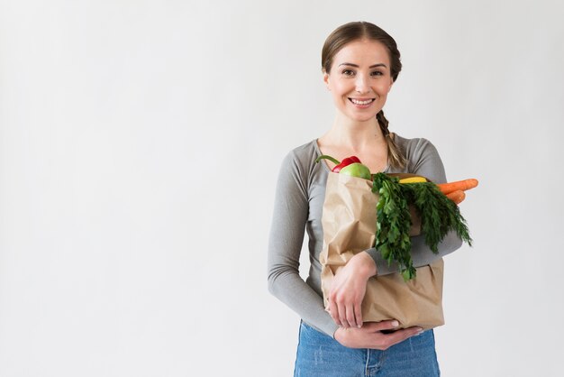 Giovane donna di smiley che tiene sacco di carta con le verdure