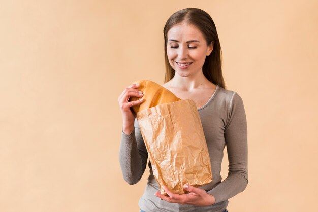 Giovane donna di smiley che tiene sacco di carta con pane